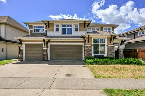 Two-story facade with stone and siding accents, dual garage doors, paved driveway, and established landscaping | Card Image