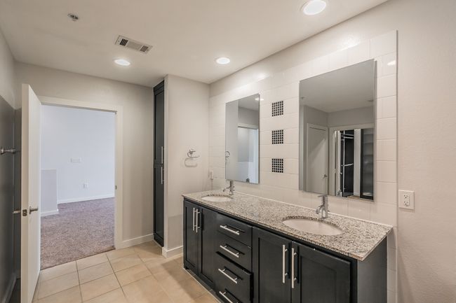 Spacious primary bath featuring double sinks, granite counters, and direct access to a custom walk-in closet. | Image 15
