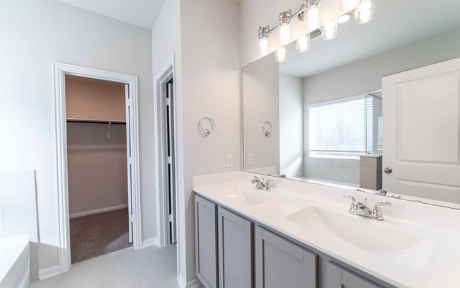 Bathroom with double vanity, tile patterned flooring, a tub to relax in, and a spacious closet | Image 18