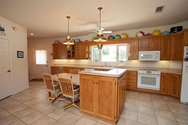 Kitchen featuring decorative light fixtures, billiards, light colored carpet, sink, and white appliances | Image 21