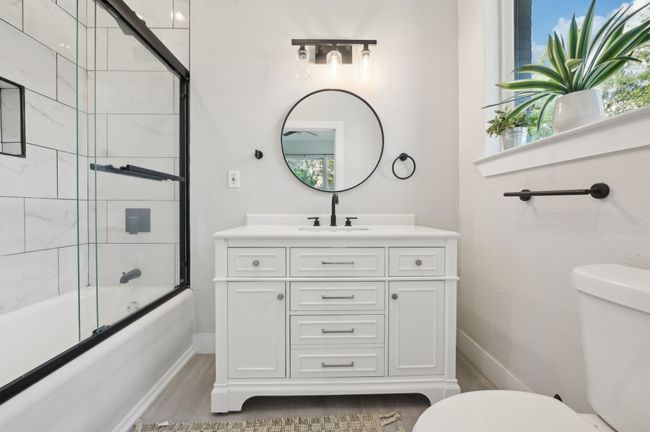 Bathroom with toilet, baseboards, wood finished floors, vanity, and enclosed tub / shower combo | Image 31