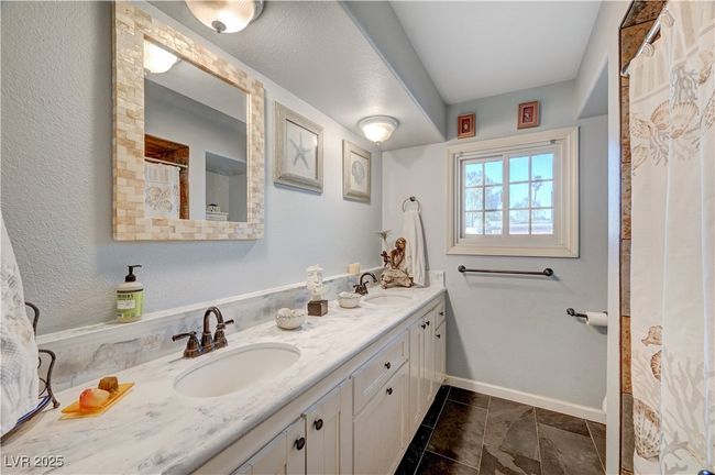 Bathroom with double vanity, tile patterned flooring, and baseboards | Image 58