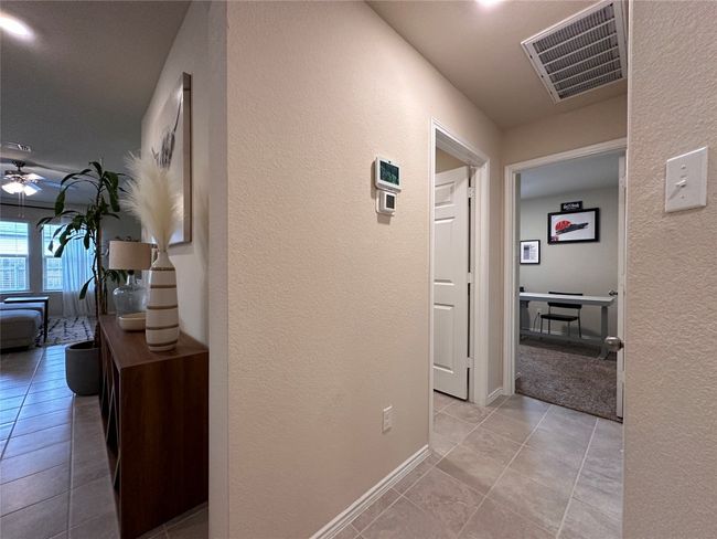Corridor with a textured wall, light tile patterned floors, and baseboards | Image 15