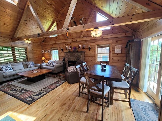 Dining room with a fireplace, wood walls, wood ceiling, light wood-type flooring, and beamed ceiling | Image 4