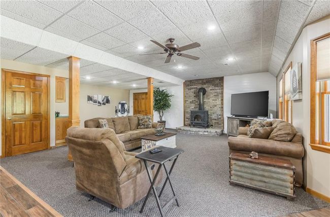 Carpeted living room featuring recessed lighting, baseboards, ceiling fan, wood finished floors, and a wood stove | Image 59