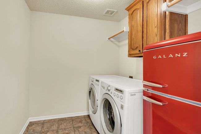 Clothes washing area with washing machine and clothes dryer, baseboards, and cabinet space | Image 33