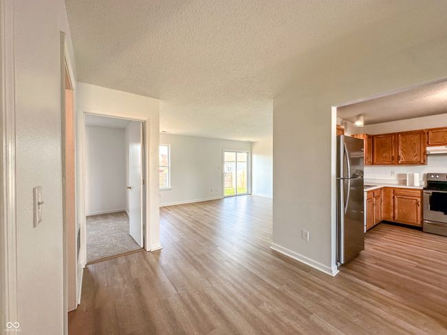 kitchen featuring open floor plan, a textured ceiling, under cabinet range hood, stainless steel appliances, and light wood-style flooring | Image 16