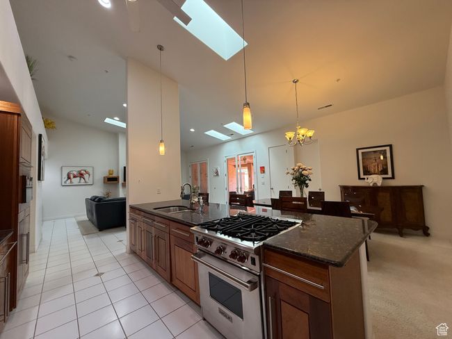 Kitchen with vaulted ceiling with skylight, dark stone countertops, a sink, high end range, and pendant lighting | Image 5