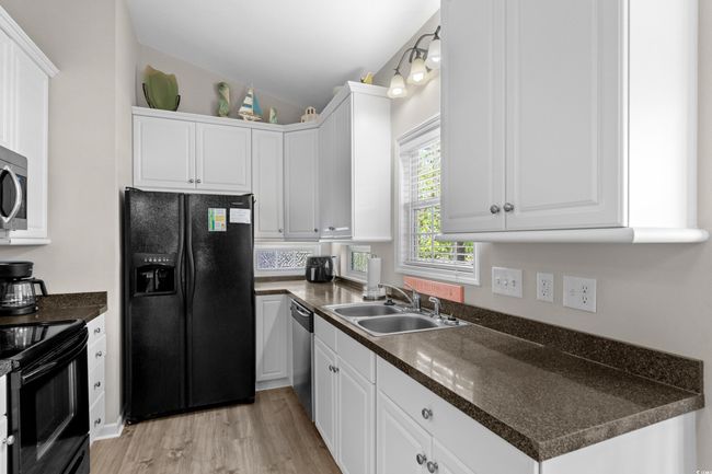 Kitchen with black appliances, lofted ceiling, white cabinetry, and a sink | Image 24