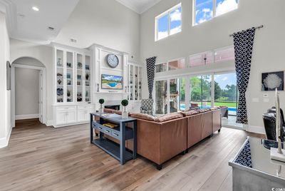 Living room featuring a towering ceiling, light hardwood / wood-style floors, and crown molding | Image 2