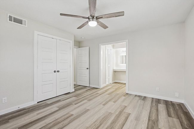 Unfurnished bedroom with connected bathroom, a closet, visible vents, baseboards, and wood finished floors | Image 27