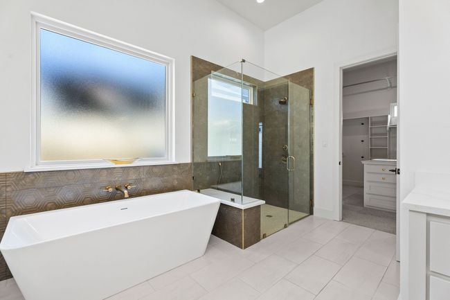 Full bathroom with a stall shower, a freestanding tub, tile patterned flooring, and a spacious closet | Image 17