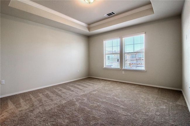 Spare room featuring ornamental molding, a raised ceiling, carpet floors, and baseboards | Image 21