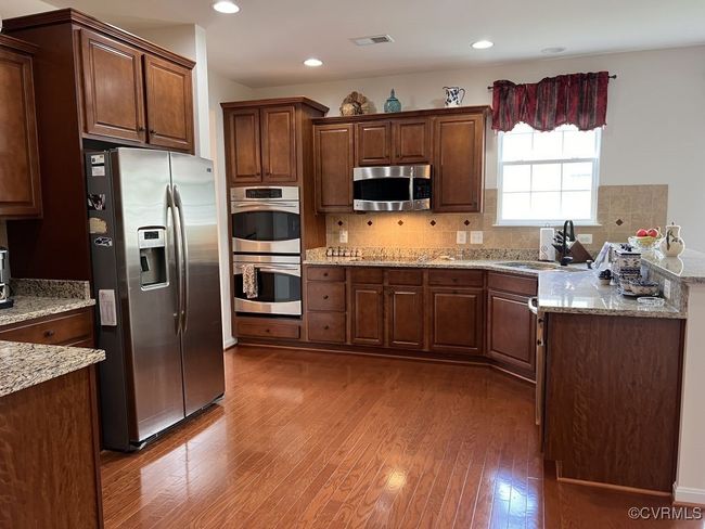 Kitchen featuring backsplash, appliances with stainless steel finishes, dark hardwood / wood-style floors, and sink | Image 17