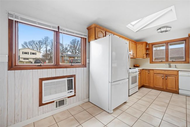 Kitchen featuring a sink, visible vents, a skylight, white appliances, and open shelves | Image 4