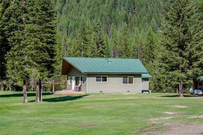 Rear view of property with a view of trees, a yard, and metal roof | Image 63