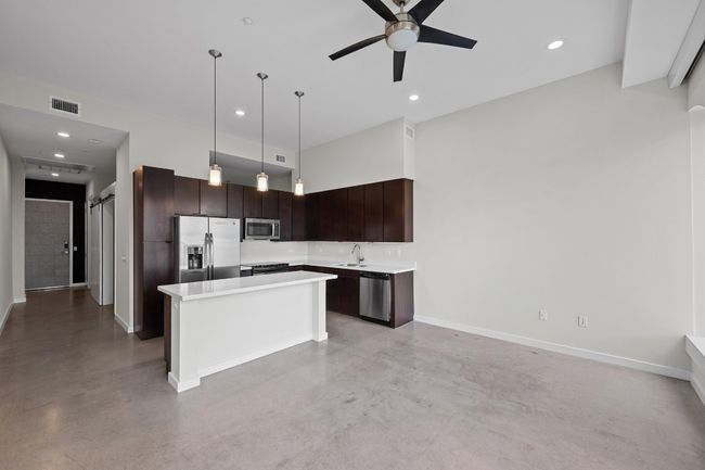 Kitchen with visible vents, finished concrete flooring, appliances with stainless steel finishes, and dark brown cabinetry | Image 9