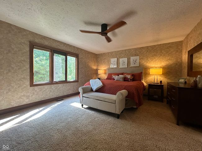 bedroom with a textured ceiling, light colored carpet, and a ceiling fan | Image 25