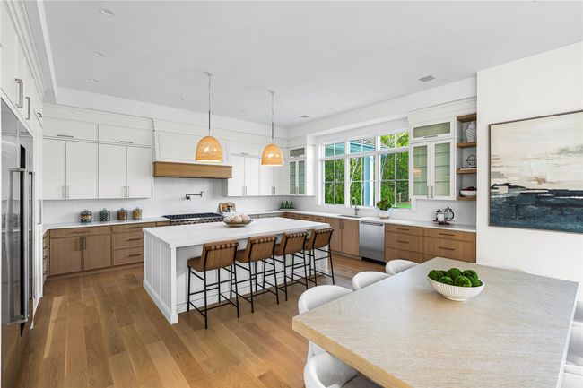 Kitchen featuring stainless steel appliances, a breakfast bar, backsplash, and light wood finished floors | Image 16