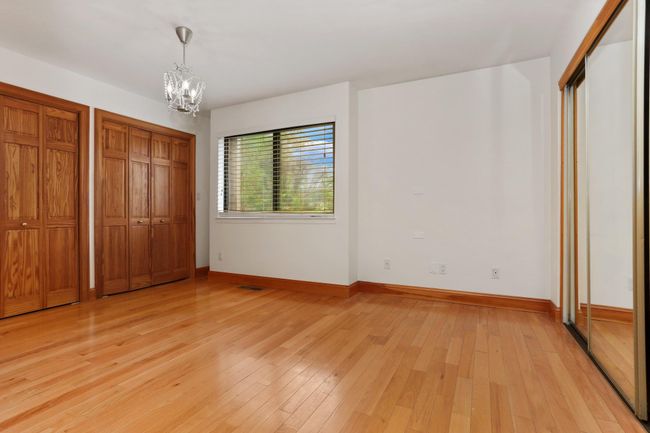 Unfurnished bedroom with a chandelier, light wood finished floors, baseboards, and two closets | Image 29