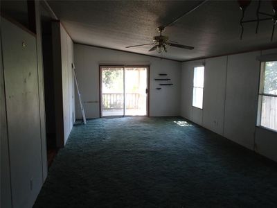 Empty room with ceiling fan, vaulted ceiling, carpet, and a healthy amount of sunlight | Image 3