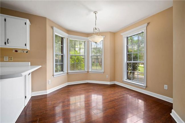 Unfurnished dining area with dark wood-style flooring and baseboards | Image 12