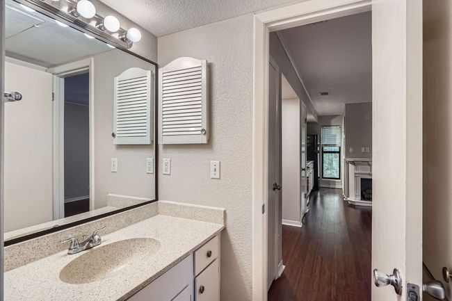 Bathroom featuring vanity, wood finished floors, radiator heating unit, a textured ceiling, and a textured wall | Image 11