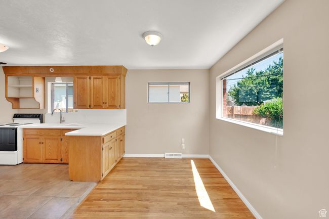 Kitchen featuring white electric range oven, a peninsula, light countertops, baseboards, and open shelves | Image 8