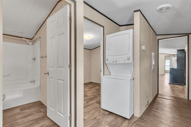 Laundry room featuring stacked washer / dryer, a textured ceiling, and wood finished floors | Image 12