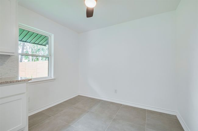 Empty room with ceiling fan and light tile patterned flooring | Image 16