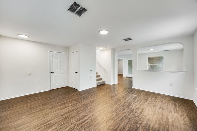 Unfurnished living room featuring arched walkways, wood finished floors, stairs, baseboards, and recessed lighting | Image 7