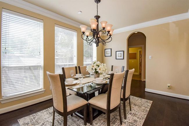 Oversized windows and dark hardwood floors create a striking backdrop in this refined dining space. A classic chandelier centers the room, offering ambiance for both weekday meals and special occasions. | Image 5