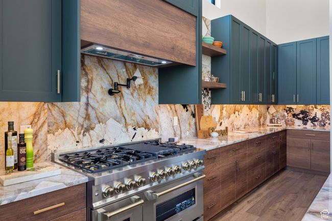 Kitchen with range with two ovens, backsplash, open shelves, and light stone countertops | Image 31