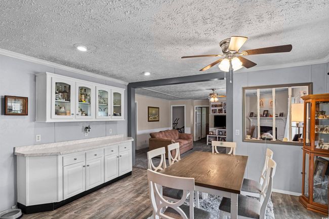 Dining room featuring ceiling fan, dark wood-type flooring, ornamental molding, and a textured ceiling | Image 34
