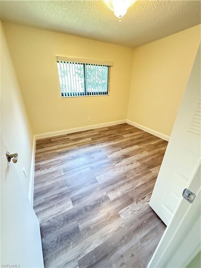 Empty room with wood finished floors, a textured ceiling, and baseboards | Image 13