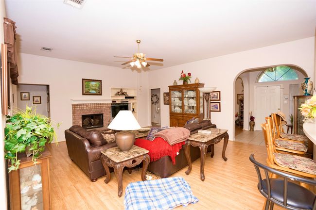 Living room featuring arched walkways, ceiling fan, light wood-type flooring, and a brick fireplace | Image 4