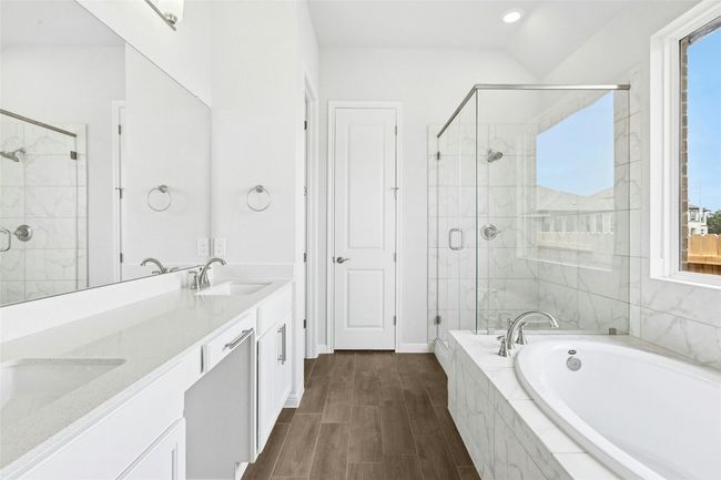 Bathroom with a bath, a stall shower, double vanity, wood finished floors, and baseboards | Image 12