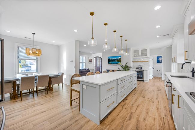 Kitchen with light wood-style floors, a sink, a center island, and tasteful backsplash | Image 18