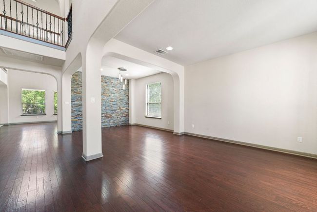 Unfurnished living room with arched walkways, healthy amount of natural light, and hardwood / wood-style floors | Image 6