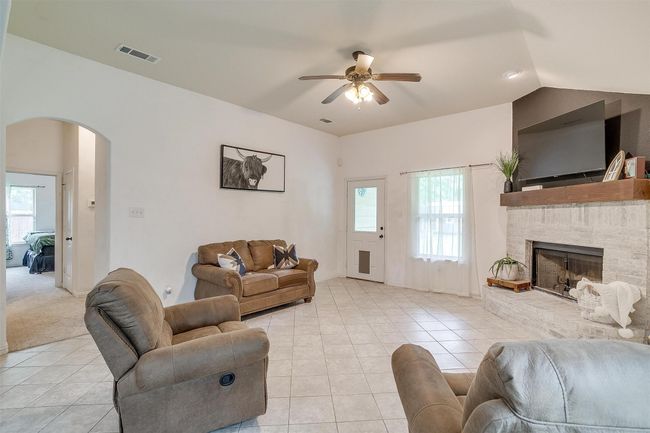 Living room with arched walkways, ceiling fan, light tile patterned floors, a fireplace, and lofted ceiling | Image 16