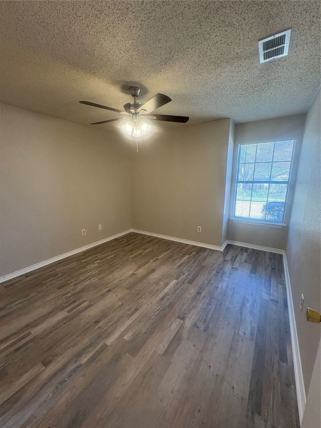 Unfurnished room featuring a textured ceiling, visible vents, baseboards, a ceiling fan, and dark wood finished floors | Image 14