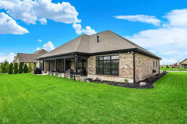 rear view of house with brick siding, a patio area, a lawn, and a shingled roof | Image 43