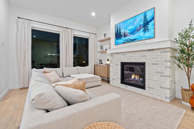 Living room with a brick fireplace, recessed lighting, wood finished floors, and baseboards | Image 8