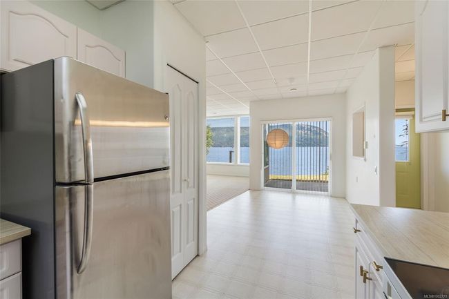 Kitchen with freestanding refrigerator, a drop ceiling, light flooring, and white cabinets | Image 45