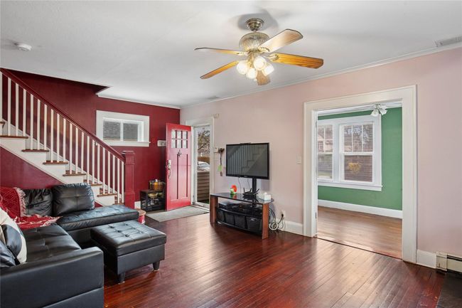 Living area featuring stairway, a ceiling fan, crown molding, visible vents, and wood-type flooring | Image 5