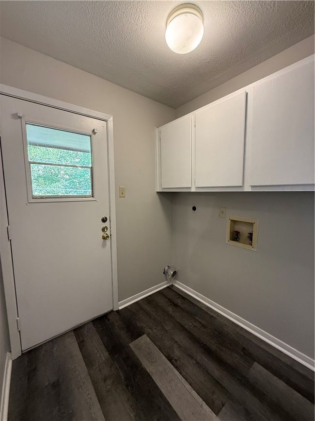 Laundry room with a textured ceiling, dark wood-style floors, hookup for a washing machine, and cabinet space | Image 12