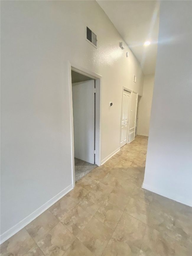 Corridor featuring a towering ceiling, visible vents, and baseboards | Image 5