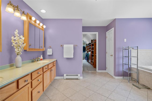 Full bath featuring a sink, double vanity, tile patterned floors, baseboards, and a baseboard heating unit | Image 18