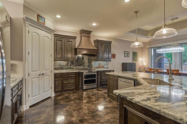As you step into the kitchen, your eye is drawn to the custom vent hood above the gas range and the stunning granite countertops. A generous walk-in corner pantry offers versatile storage space to keep everything organized and within reach. | Image 22