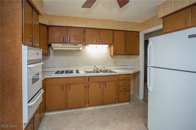 Kitchen with white appliances, a warming drawer, under cabinet range hood, and light countertops | Image 16